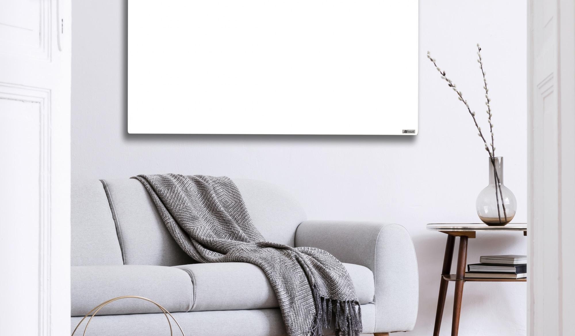 Helles Wohnzimmer mit grauem Sofa, Decke, Vase und leerer Leinwand an der Wand.