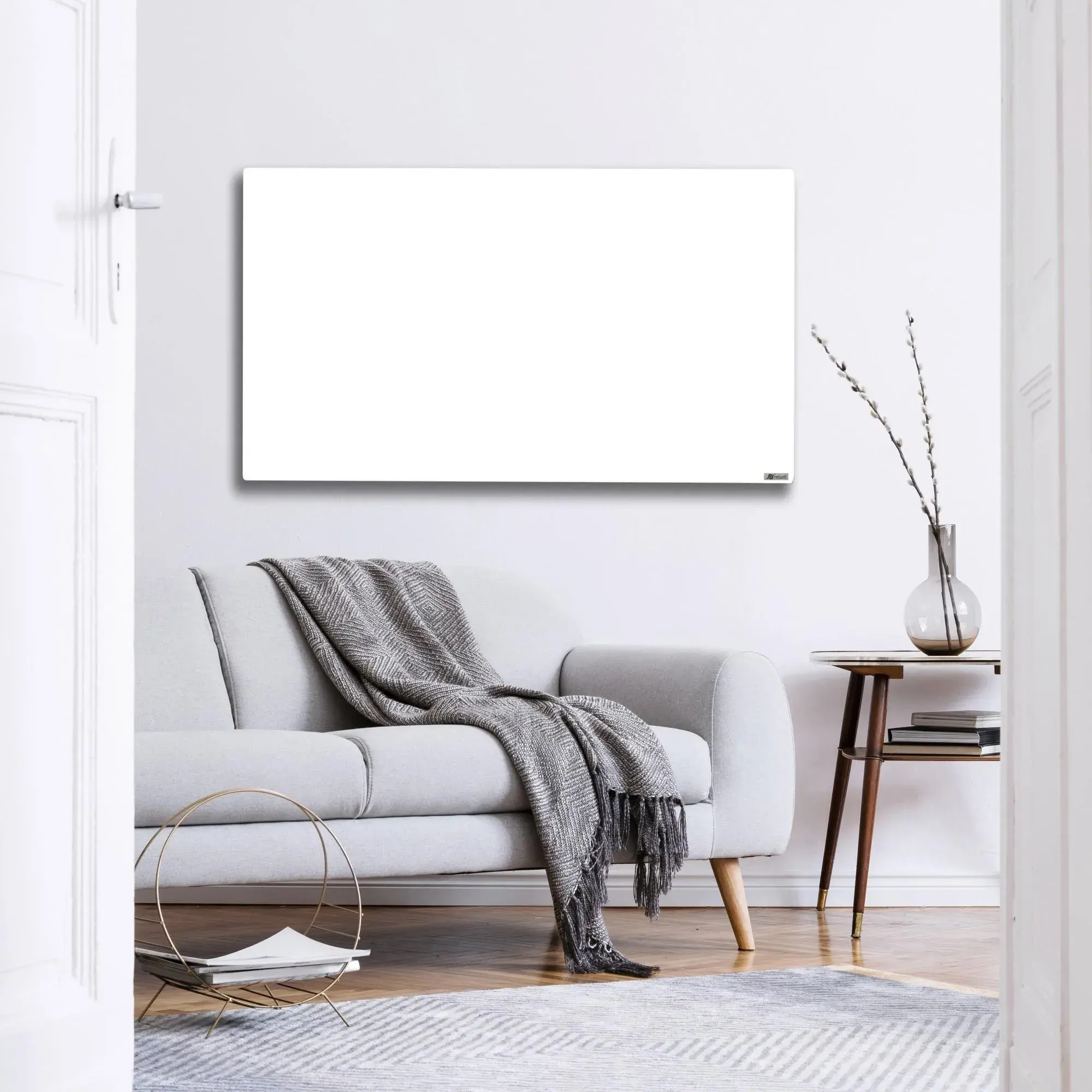 Helles Wohnzimmer mit grauem Sofa, Decke, Vase und leerer Leinwand an der Wand.